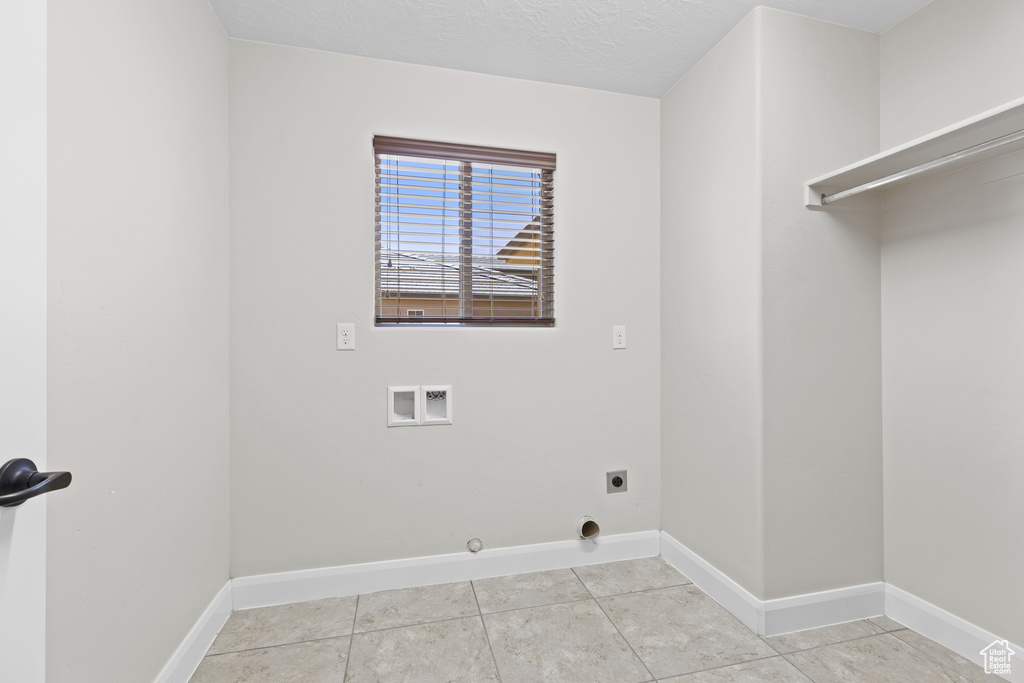 Washroom with washer hookup, electric dryer hookup, baseboards, light tile patterned flooring, and hookup for a gas dryer