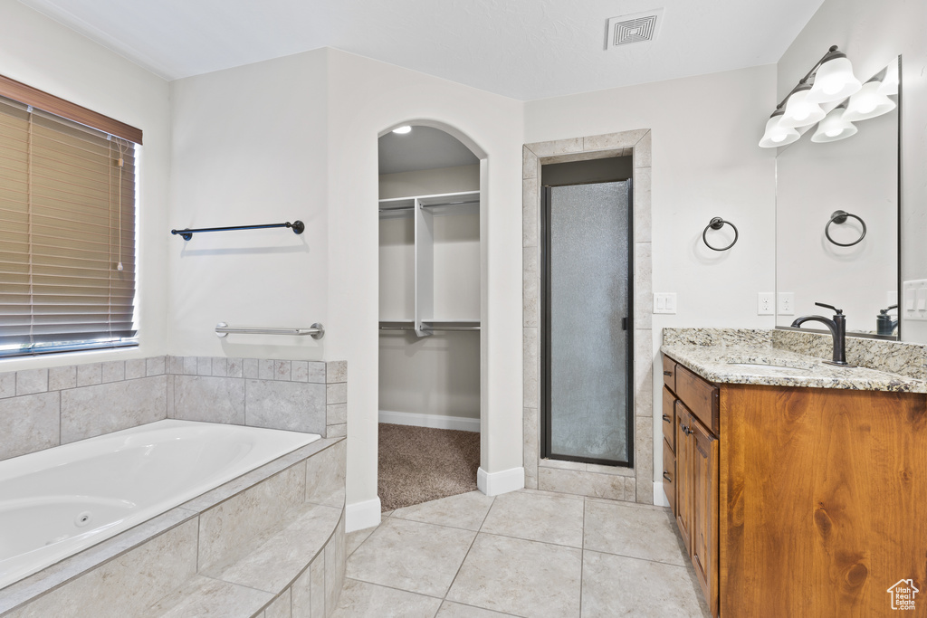 Bathroom featuring a stall shower, vanity, a spacious closet, and a jetted tub