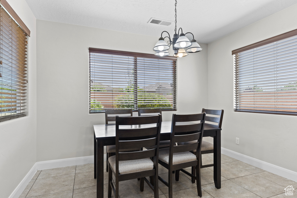 Dining space with a chandelier, plenty of natural light, and light tile patterned floors