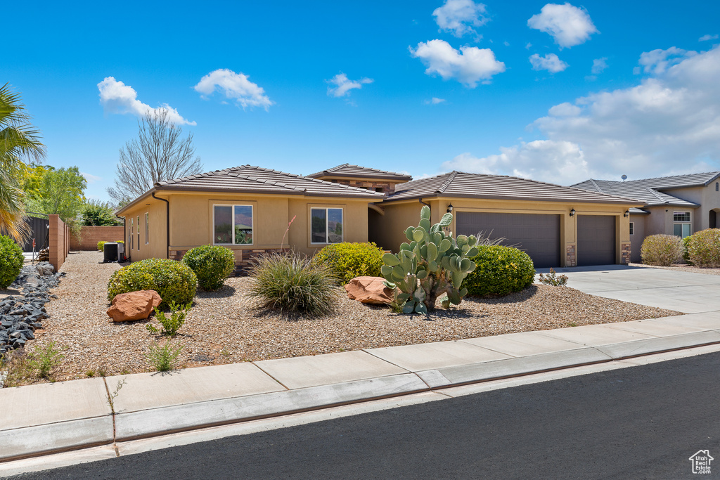 View of front of home featuring a garage, stucco siding, concrete driveway, and a tile roof