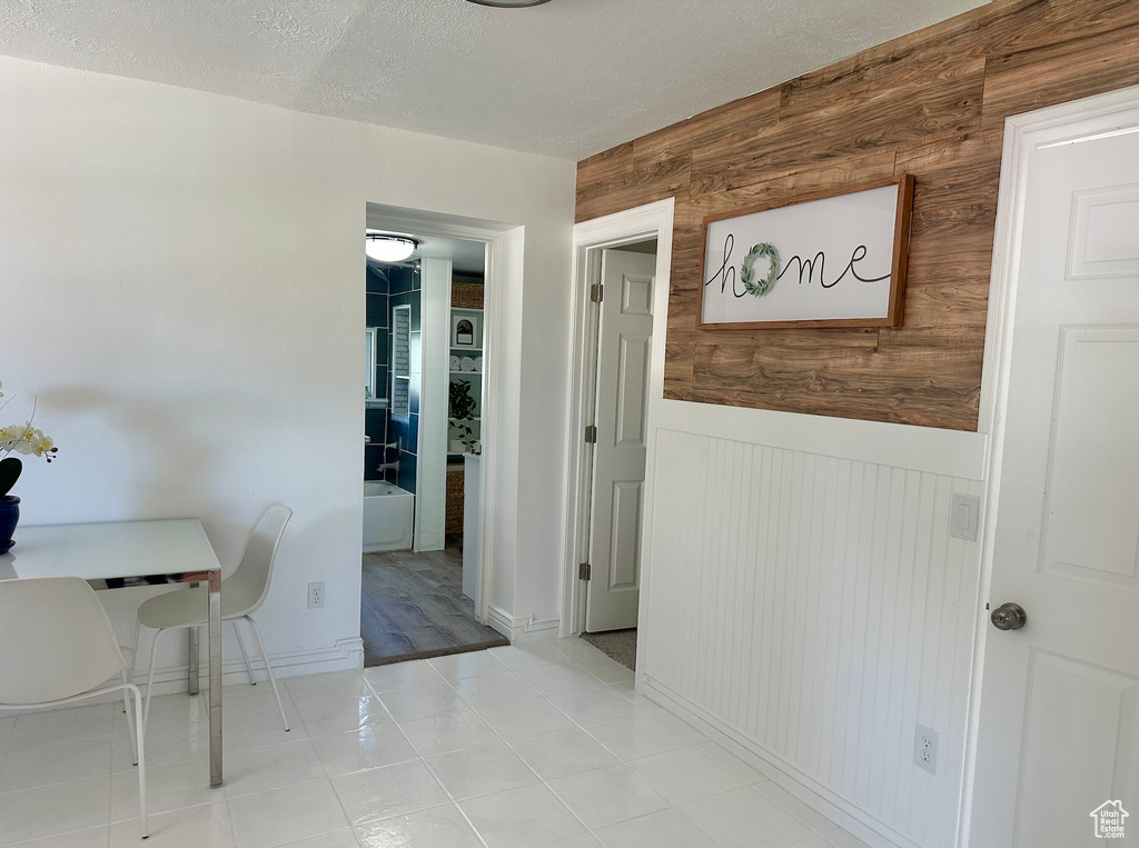 Dining space with a wainscoted wall, wood walls, and a textured ceiling