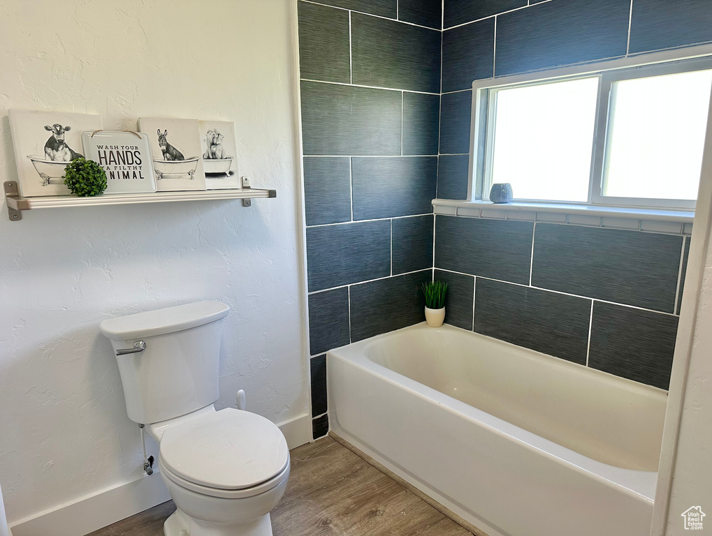 Bathroom with wood finished floors, toilet, and baseboards