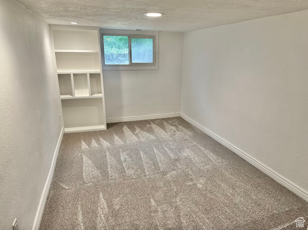 Spare room featuring carpet, baseboards, and a textured ceiling