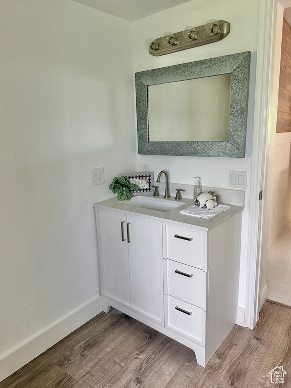 Bathroom featuring wood finished floors, vanity, and baseboards