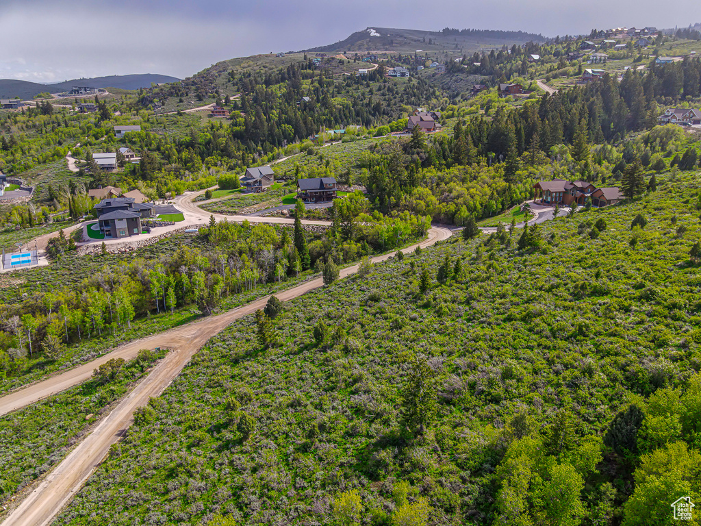 Aerial view of property and surrounding area with a mountain backdrop and a heavily wooded area