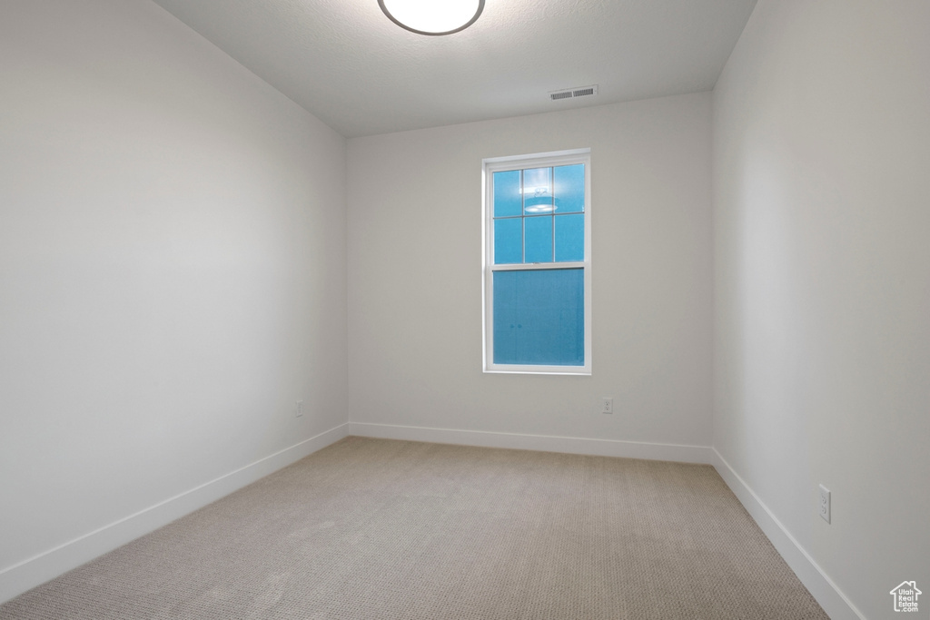 Empty room featuring light colored carpet and baseboards