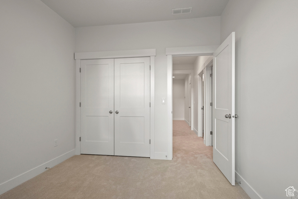 Unfurnished bedroom featuring light carpet, baseboards, and a closet