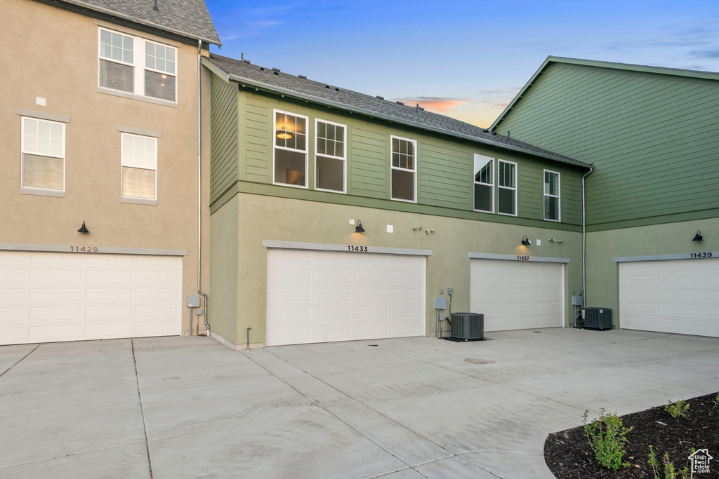 Back of property with an attached garage, stucco siding, and driveway