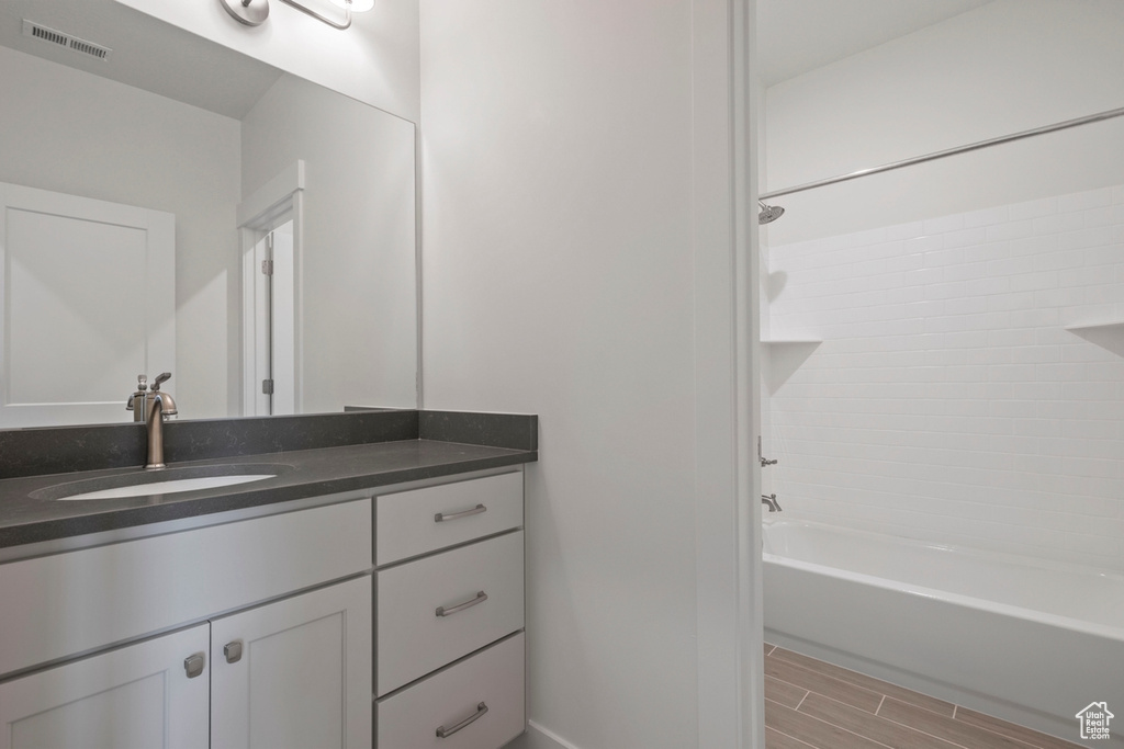 Bathroom featuring vanity, bathing tub / shower combination, wood tiled floors, and baseboards