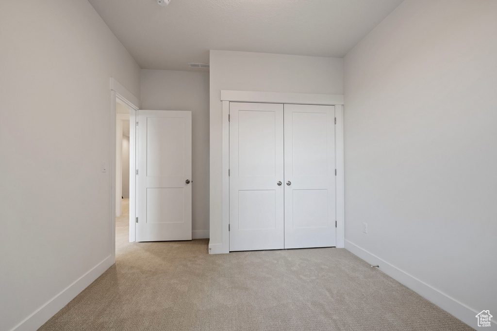 Unfurnished bedroom featuring carpet flooring, baseboards, and a closet