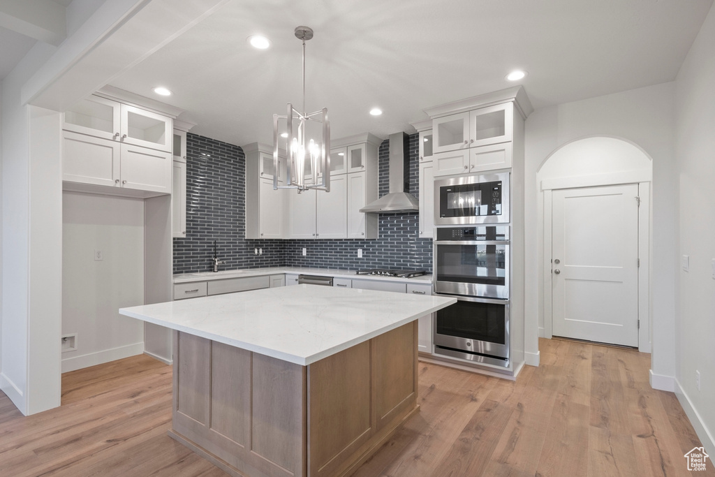 Kitchen featuring wall chimney exhaust hood, stainless steel appliances, tasteful backsplash, white cabinets, and recessed lighting