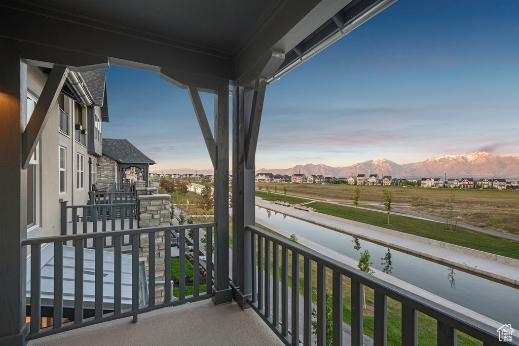 Balcony at dusk featuring a water and mountain view