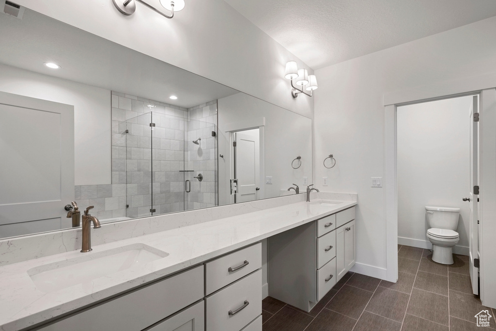 Full bath featuring double vanity, a stall shower, toilet, baseboards, and recessed lighting