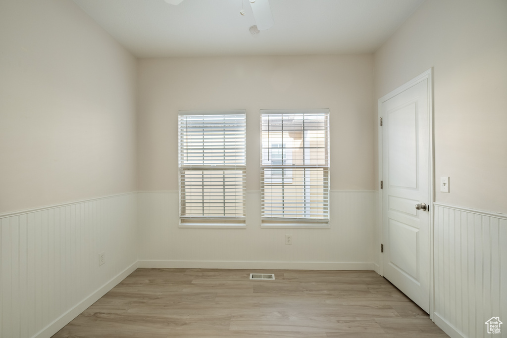 Spare room featuring wainscoting, light wood-style floors, and ceiling fan
