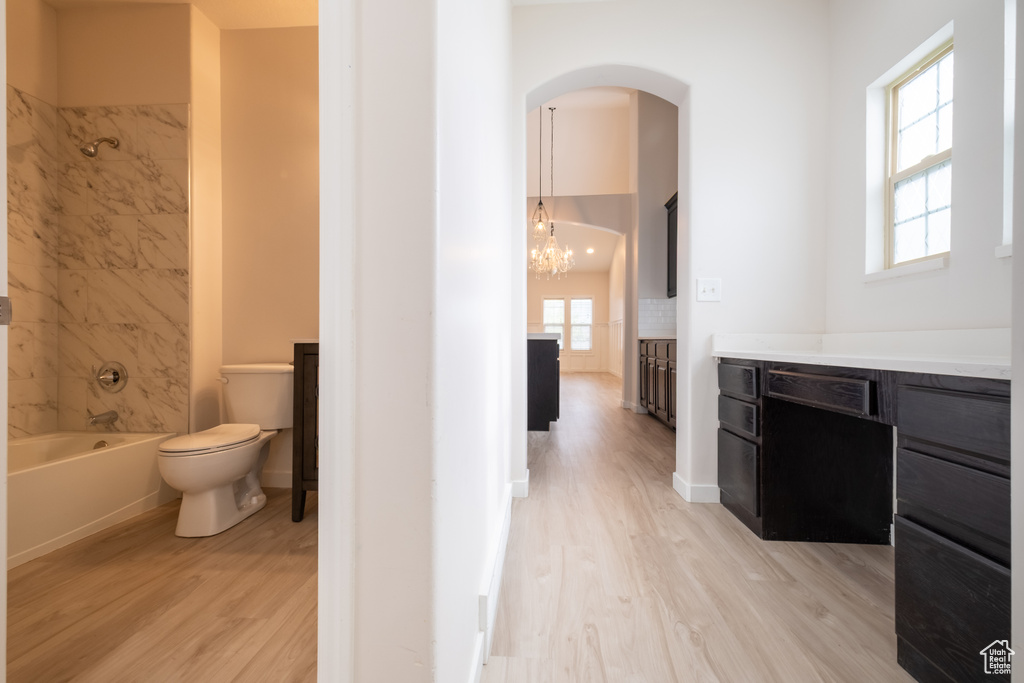 Bathroom featuring wood finished floors, vanity, toilet, tub / shower combination, and a chandelier