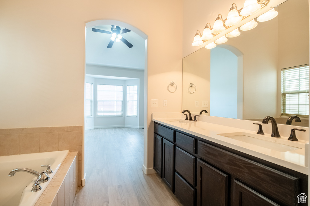 Full bathroom with wood finished floors, double vanity, a bath, and plenty of natural light