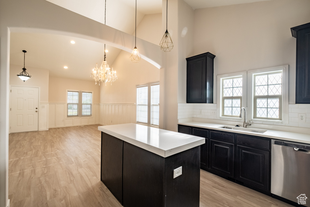 Kitchen featuring dishwasher, dark cabinetry, a sink, a wainscoted wall, and high vaulted ceiling