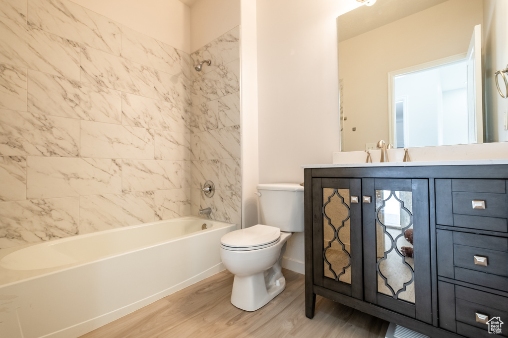 Bathroom featuring wood finished floors, toilet, vanity, bathtub / shower combination, and baseboards