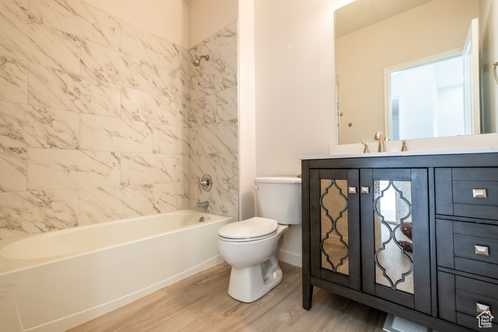Bathroom featuring wood finished floors, toilet, vanity, and bathtub / shower combination