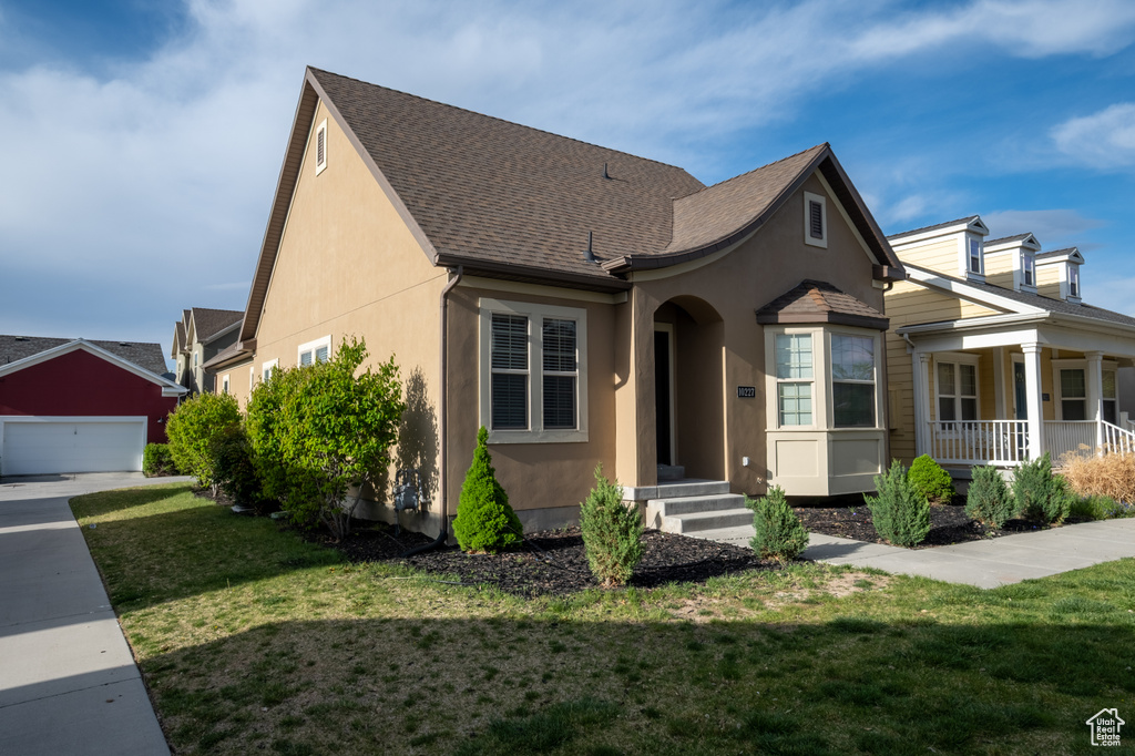 View of front of property with stucco siding, a front yard, a shingled roof, and a porch