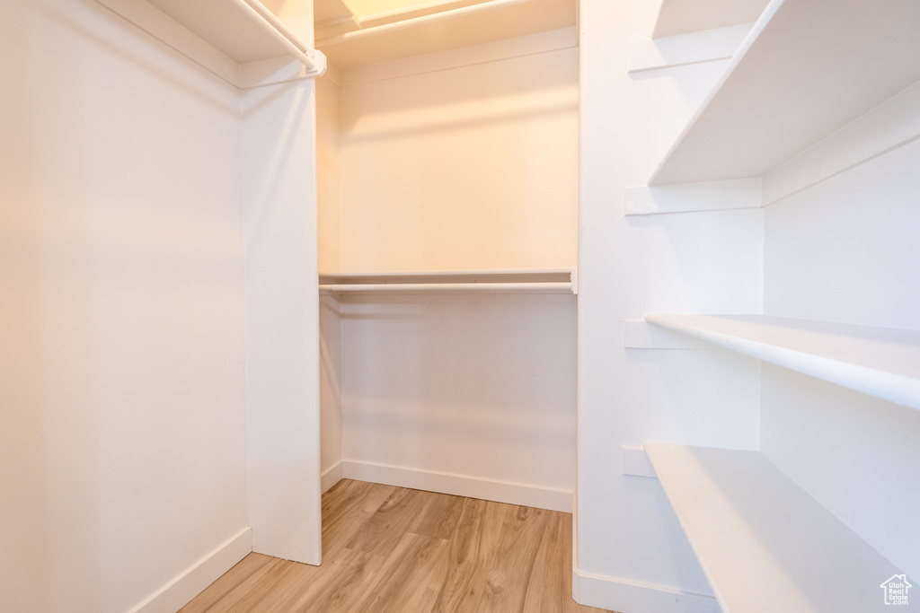 Walk in closet with light wood-style floors