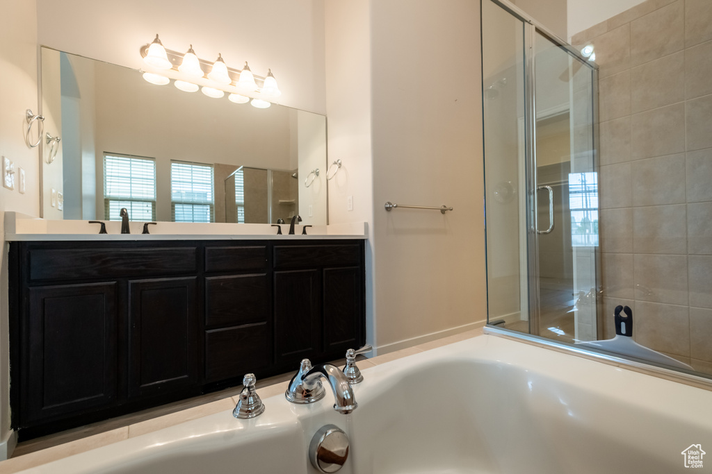 Full bathroom featuring a stall shower, double vanity, and a bath