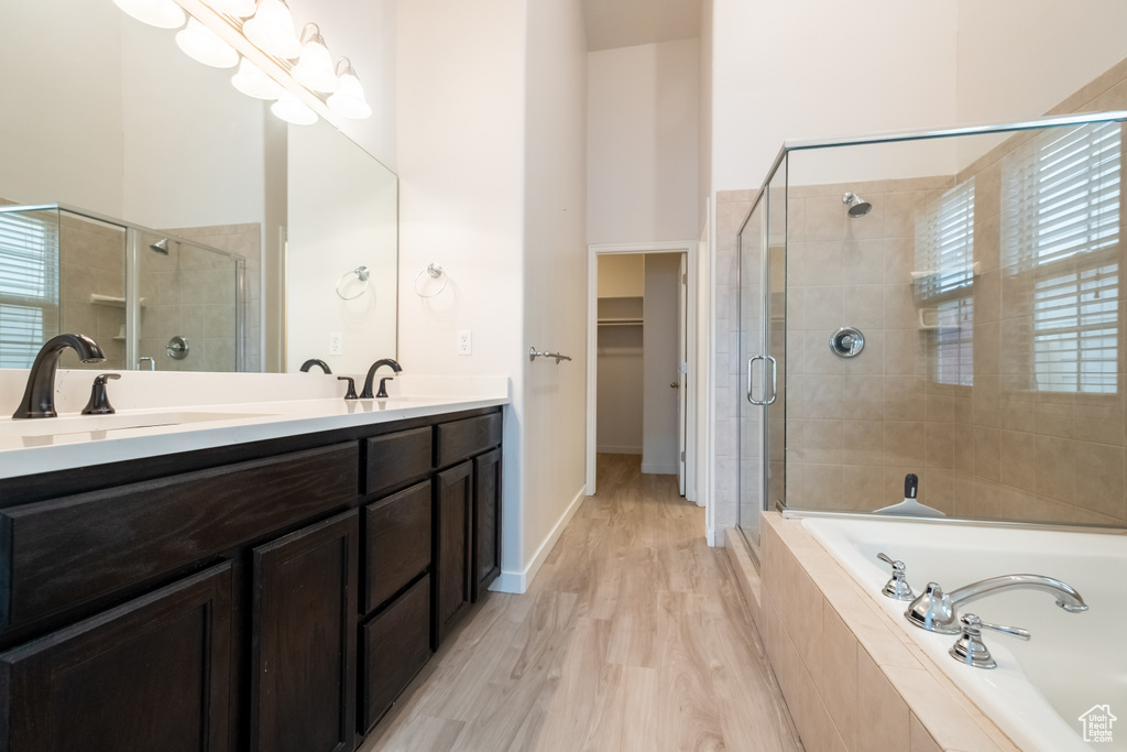 Bathroom with a stall shower, a garden tub, double vanity, and wood finished floors