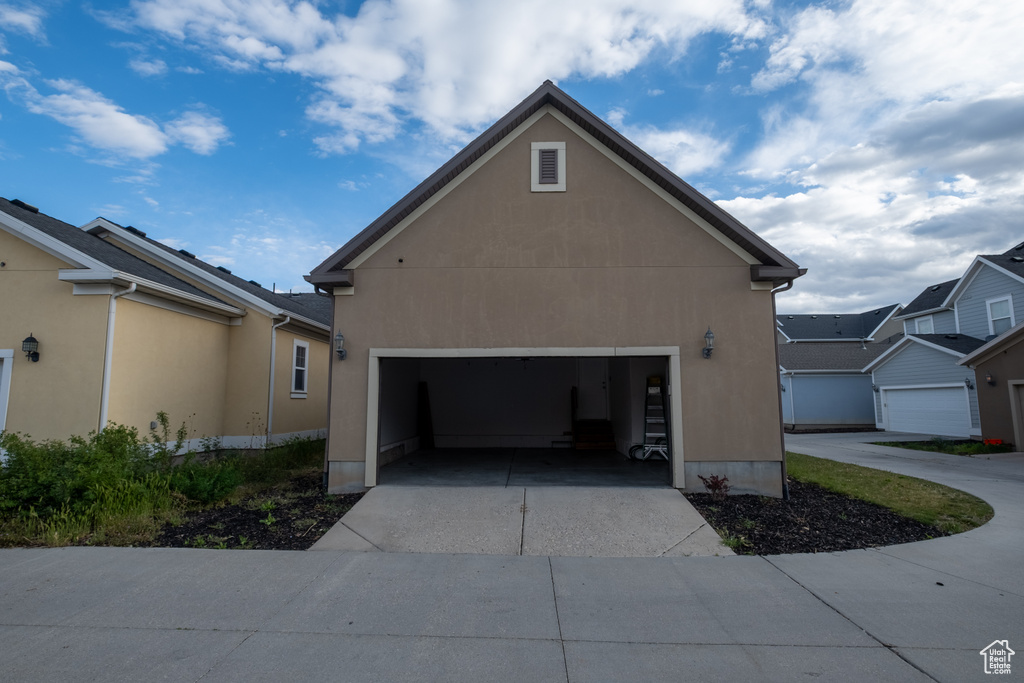 View of side of property with an attached garage, concrete driveway, and stucco siding