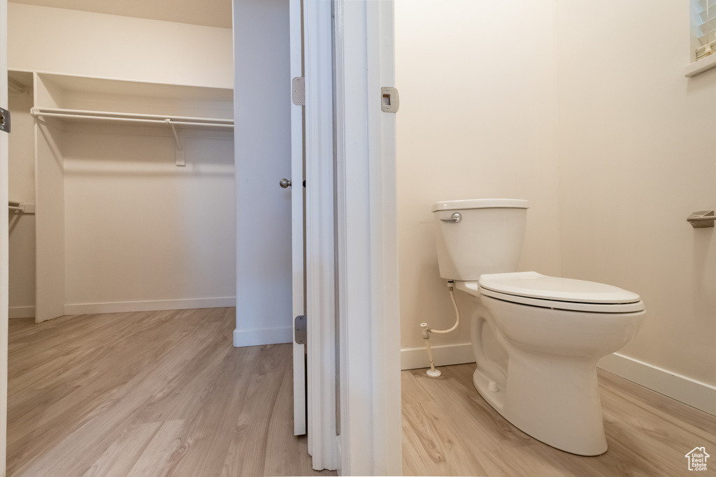 Bathroom featuring toilet, wood finished floors, baseboards, and a walk in closet