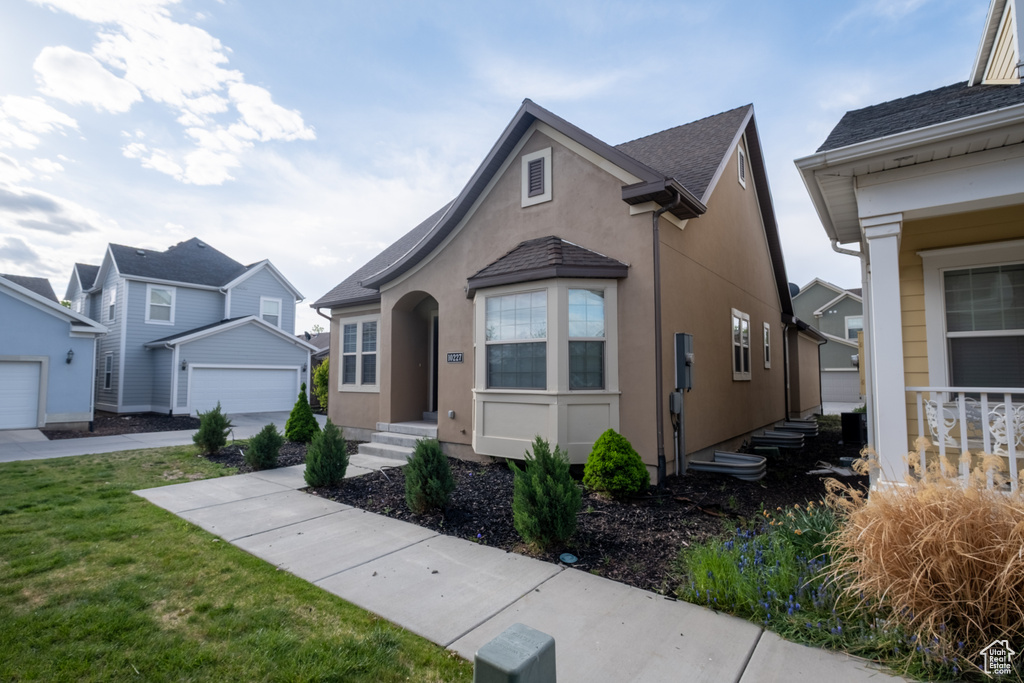 View of front of home with stucco siding, a garage, and a front lawn