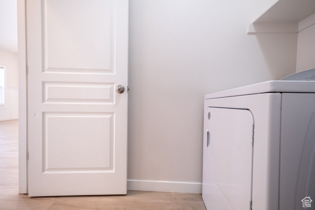Washroom with washer / clothes dryer, light wood-style floors, and baseboards