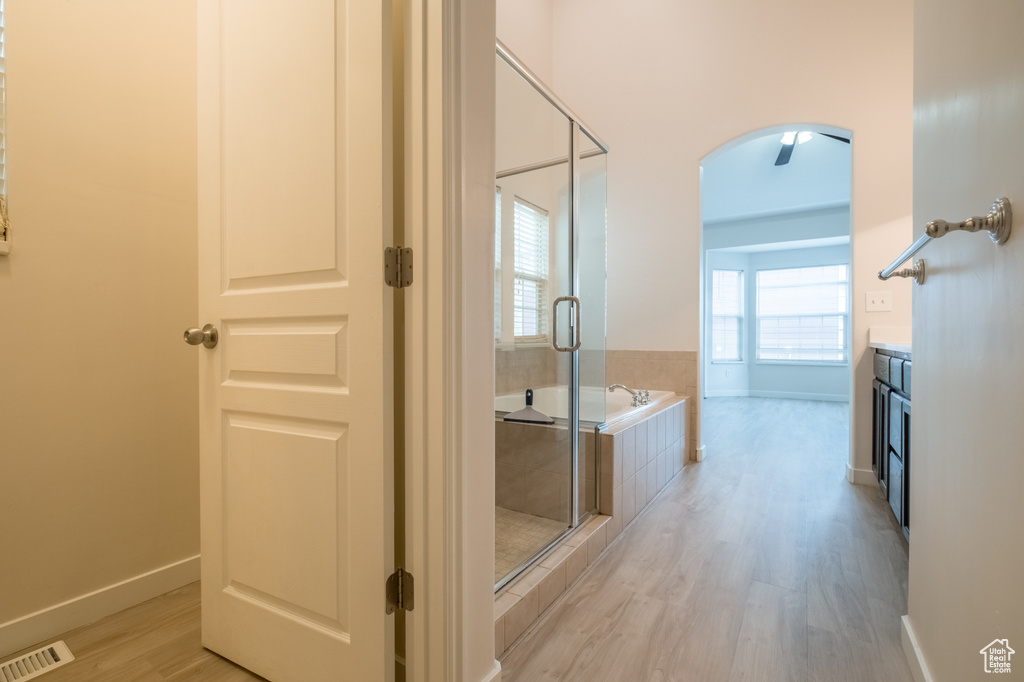 Full bath featuring wood finished floors, a shower stall, a bath, and baseboards
