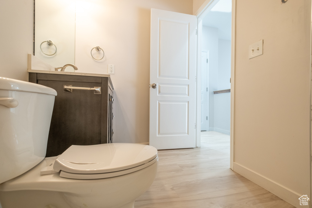 Bathroom with wood finished floors, vanity, baseboards, and toilet