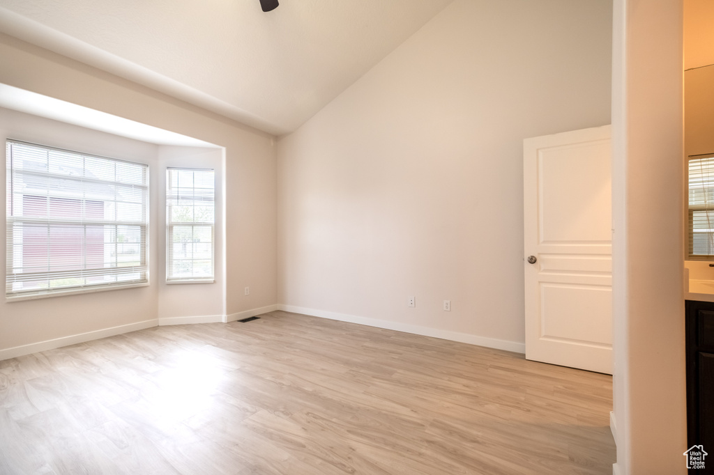 Spare room with light wood-style floors, ceiling fan, baseboards, and high vaulted ceiling