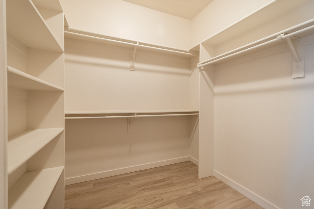 Walk in closet with light wood finished floors