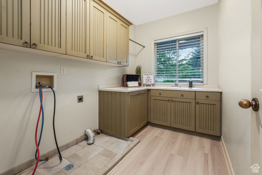 Laundry room featuring electric dryer hookup, cabinet space, washer hookup, light wood finished floors, and baseboards