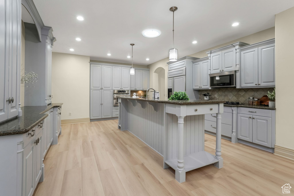 Kitchen with appliances with stainless steel finishes, light wood-style flooring, backsplash, gray cabinetry, and recessed lighting