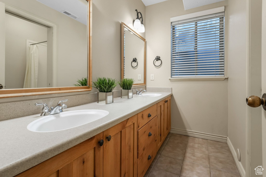 Full bathroom with tile patterned floors, double vanity, and baseboards