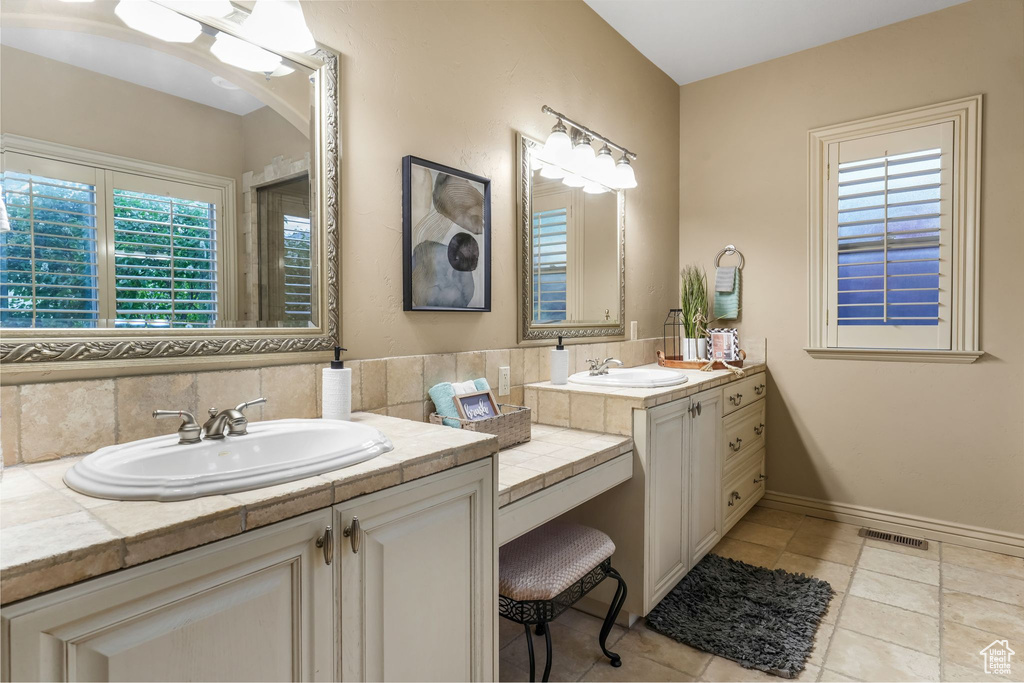Full bathroom with decorative backsplash, vanity, baseboards, and tile patterned flooring