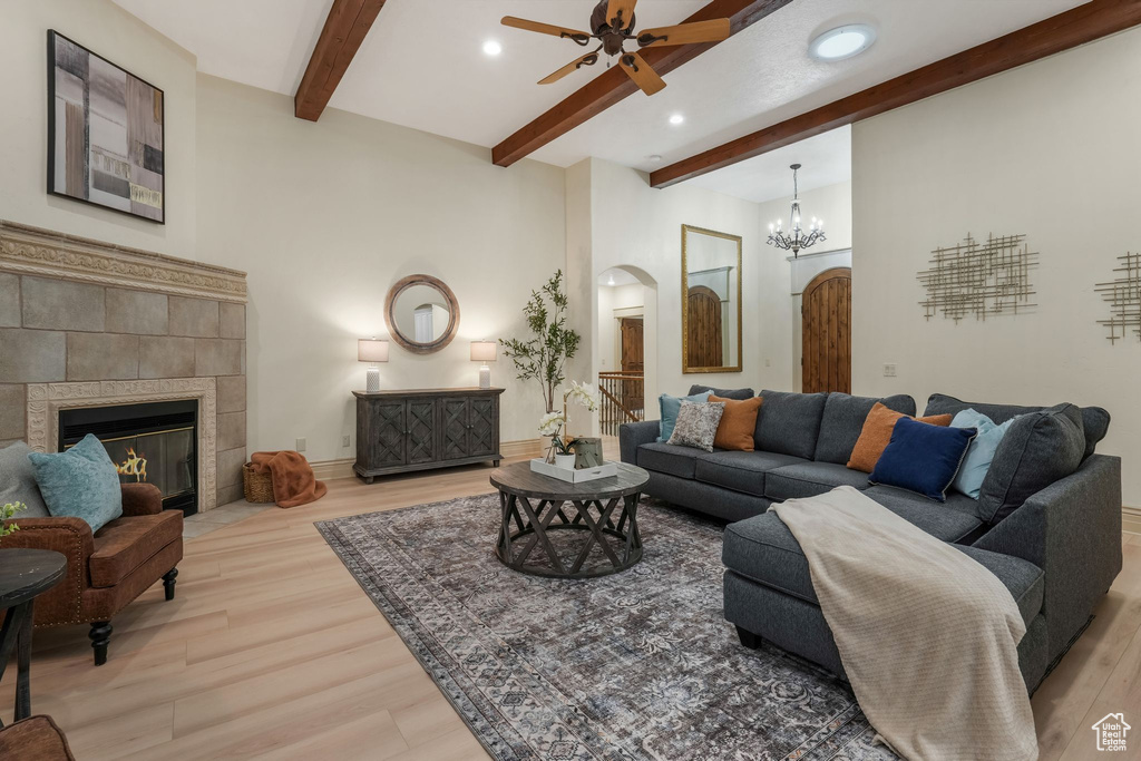 Living area featuring arched walkways, ceiling fan, light wood finished floors, beamed ceiling, and recessed lighting