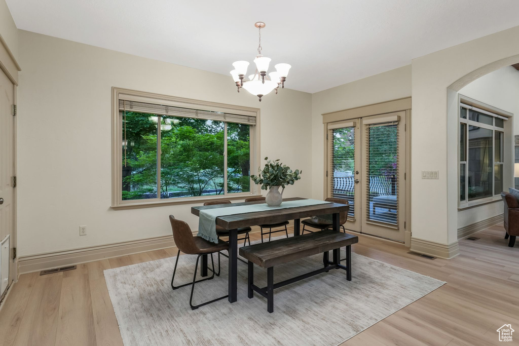 Dining area featuring a chandelier, arched walkways, light wood-style floors, and baseboards