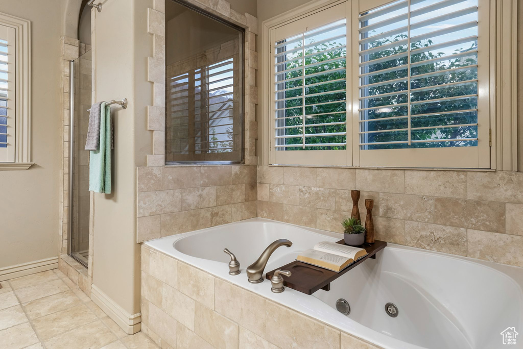 Bathroom with a whirlpool tub, baseboards, a shower stall, and tile patterned floors