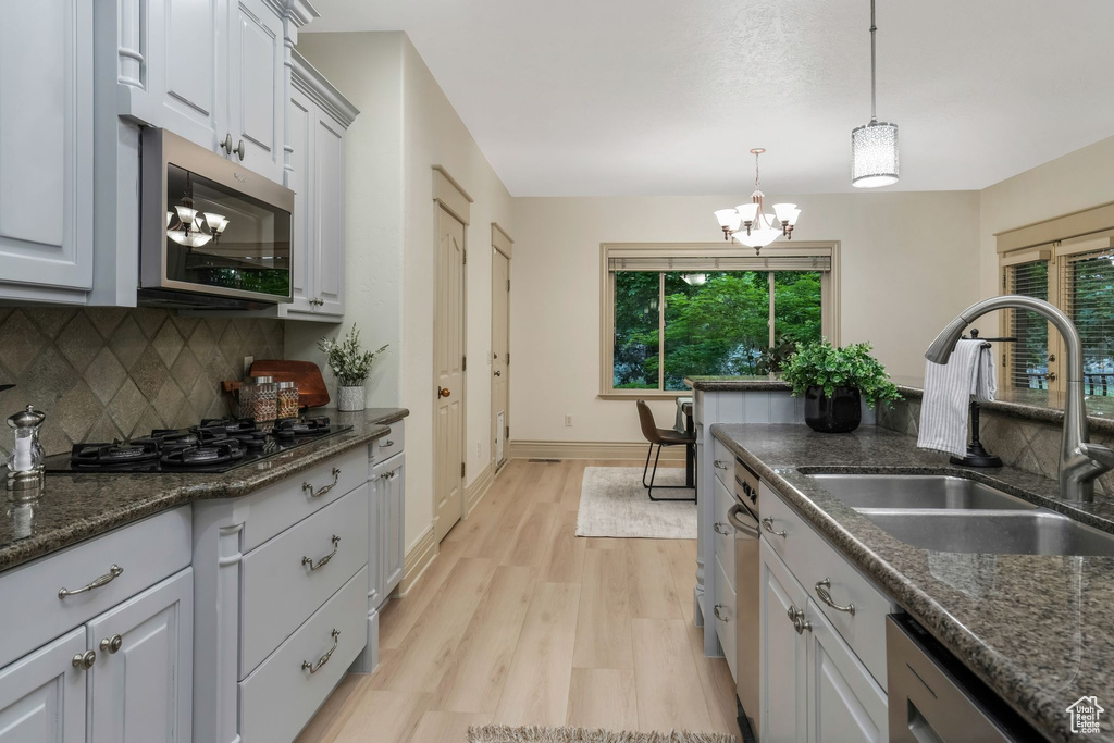 Kitchen with stainless steel appliances, a sink, a chandelier, and healthy amount of natural light