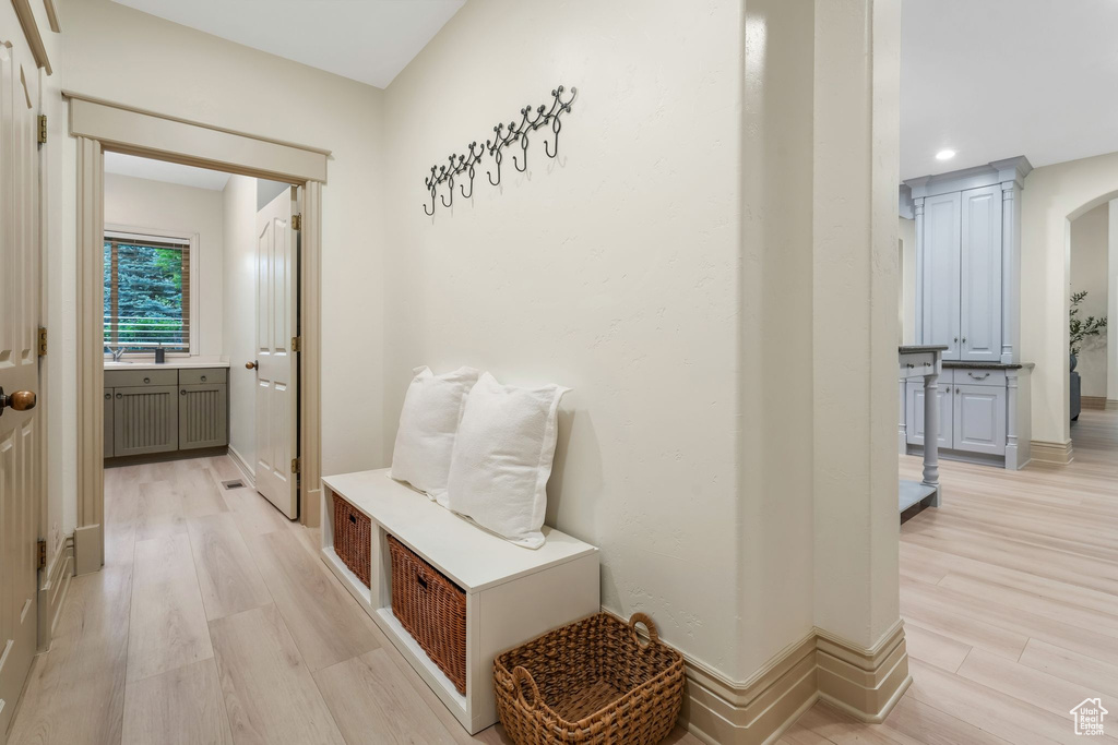 Mudroom with light wood finished floors, recessed lighting, arched walkways, and baseboards