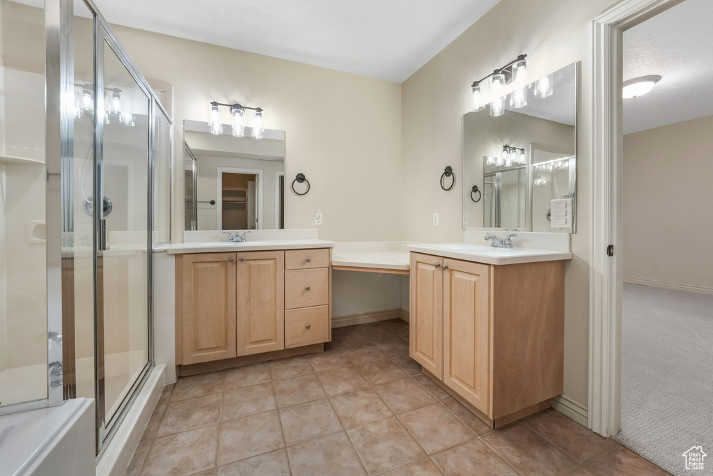 Bathroom featuring a stall shower, two vanities, tile patterned flooring, and baseboards