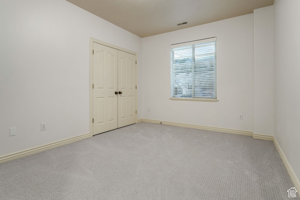 Unfurnished bedroom featuring carpet flooring, baseboards, and a closet