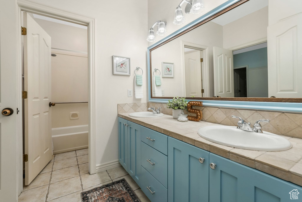 Full bathroom with tile patterned flooring, tasteful backsplash, double vanity, and shower / washtub combination