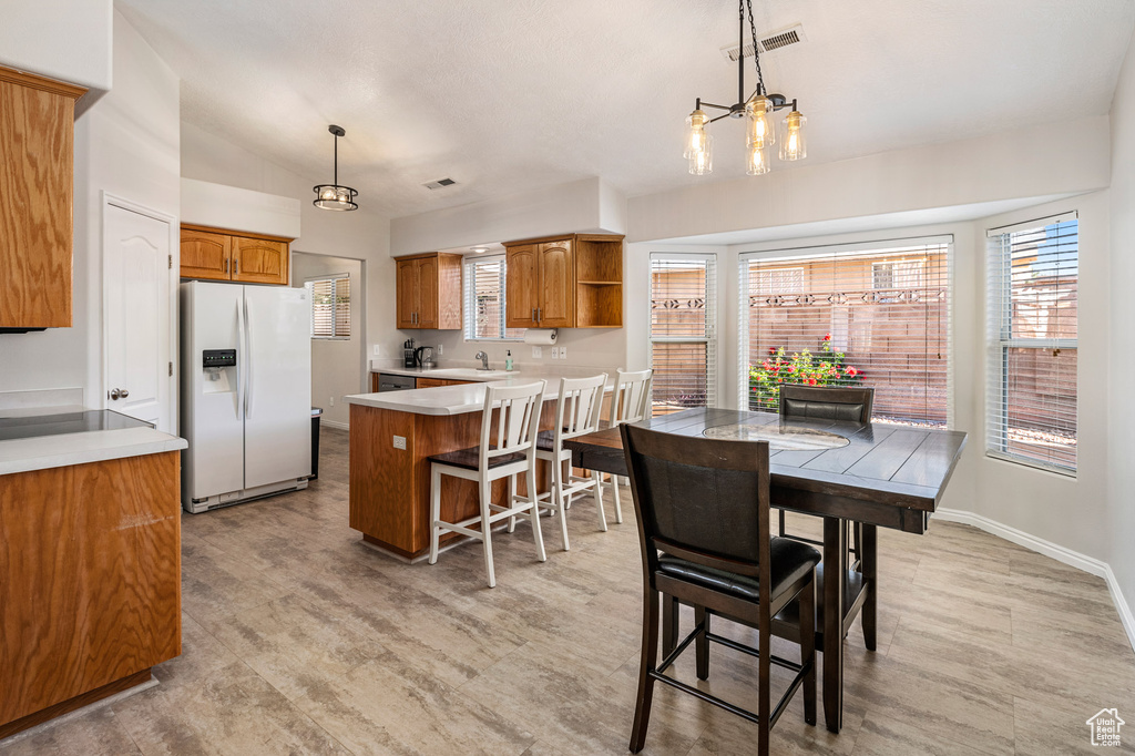 Dining space with plenty of natural light, a chandelier, light wood-style floors, and vaulted ceiling
