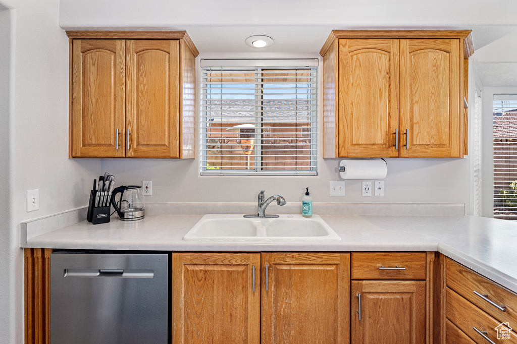 Kitchen with stainless steel dishwasher, a sink, and light countertops