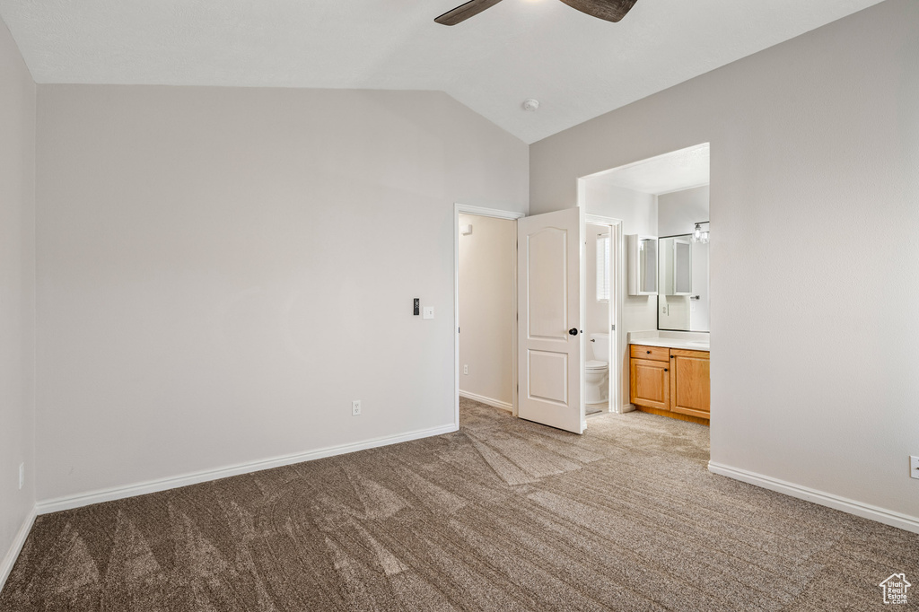 Unfurnished bedroom featuring light carpet, lofted ceiling, baseboards, connected bathroom, and a ceiling fan